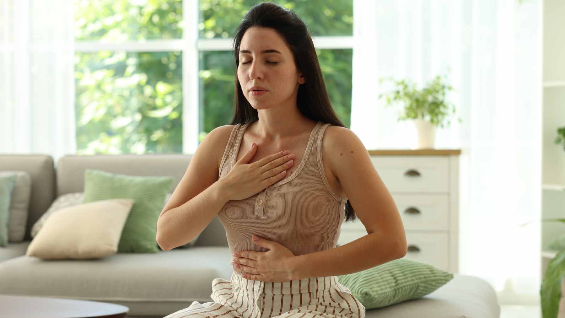 A woman practicing diaphragmatic breathing in a quiet setting to manage anxiety and lower stress levels.