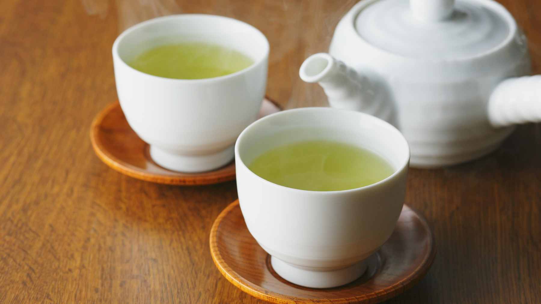 A steaming cup of green tea on a wooden table, symbolizing a heart-healthy daily habit.