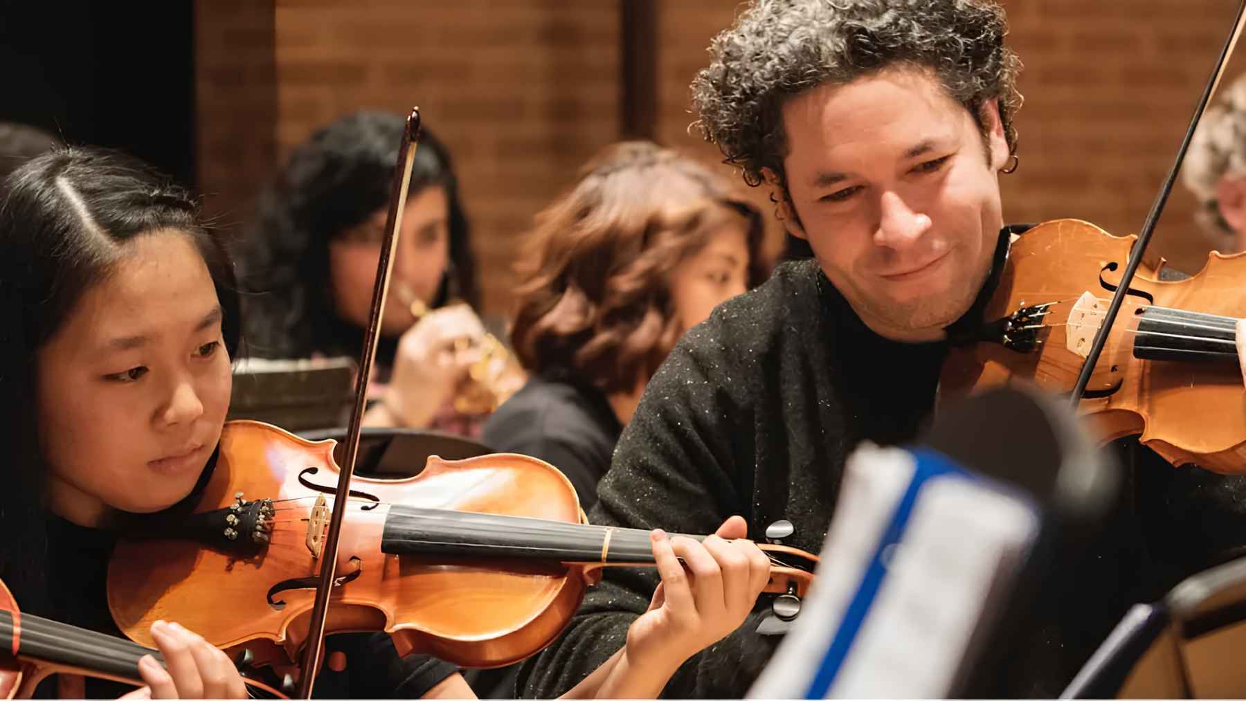 Gustavo Dudamel rehearsing with young orchestra musicians as part of a music education and youth development program