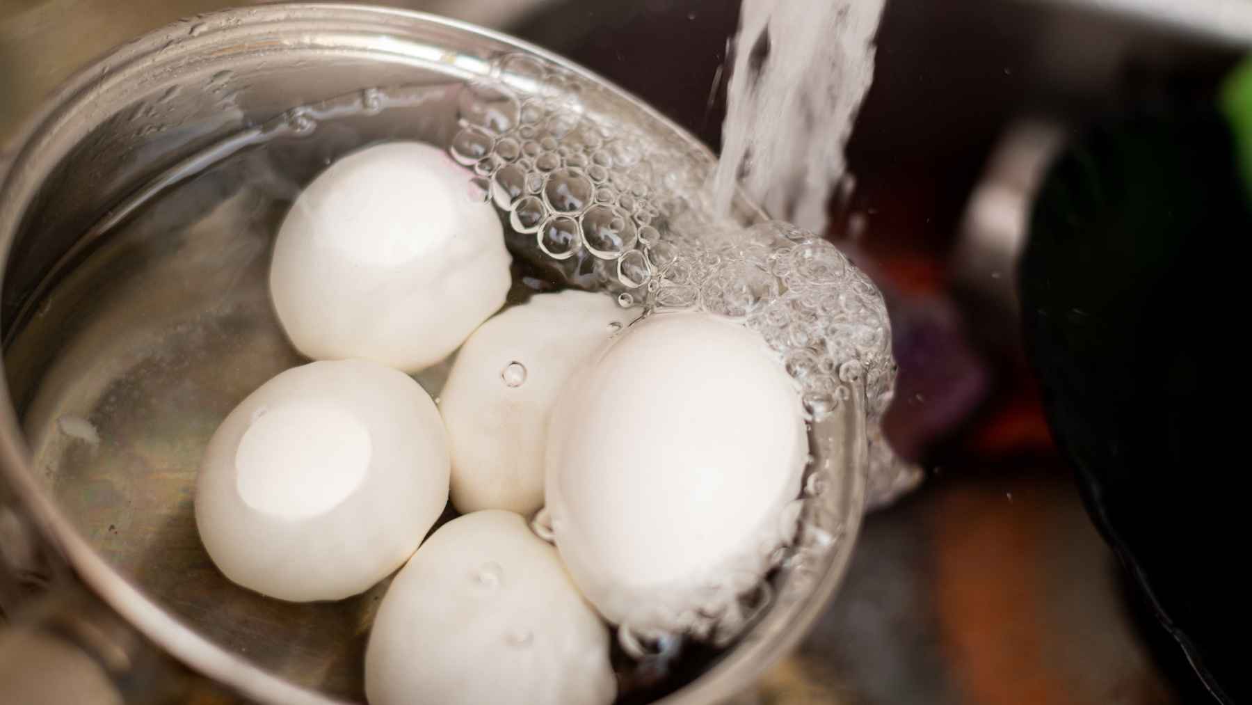 Freshly boiled eggs being cooled after cooking, illustrating proper handling techniques for hard-boiled eggs.
