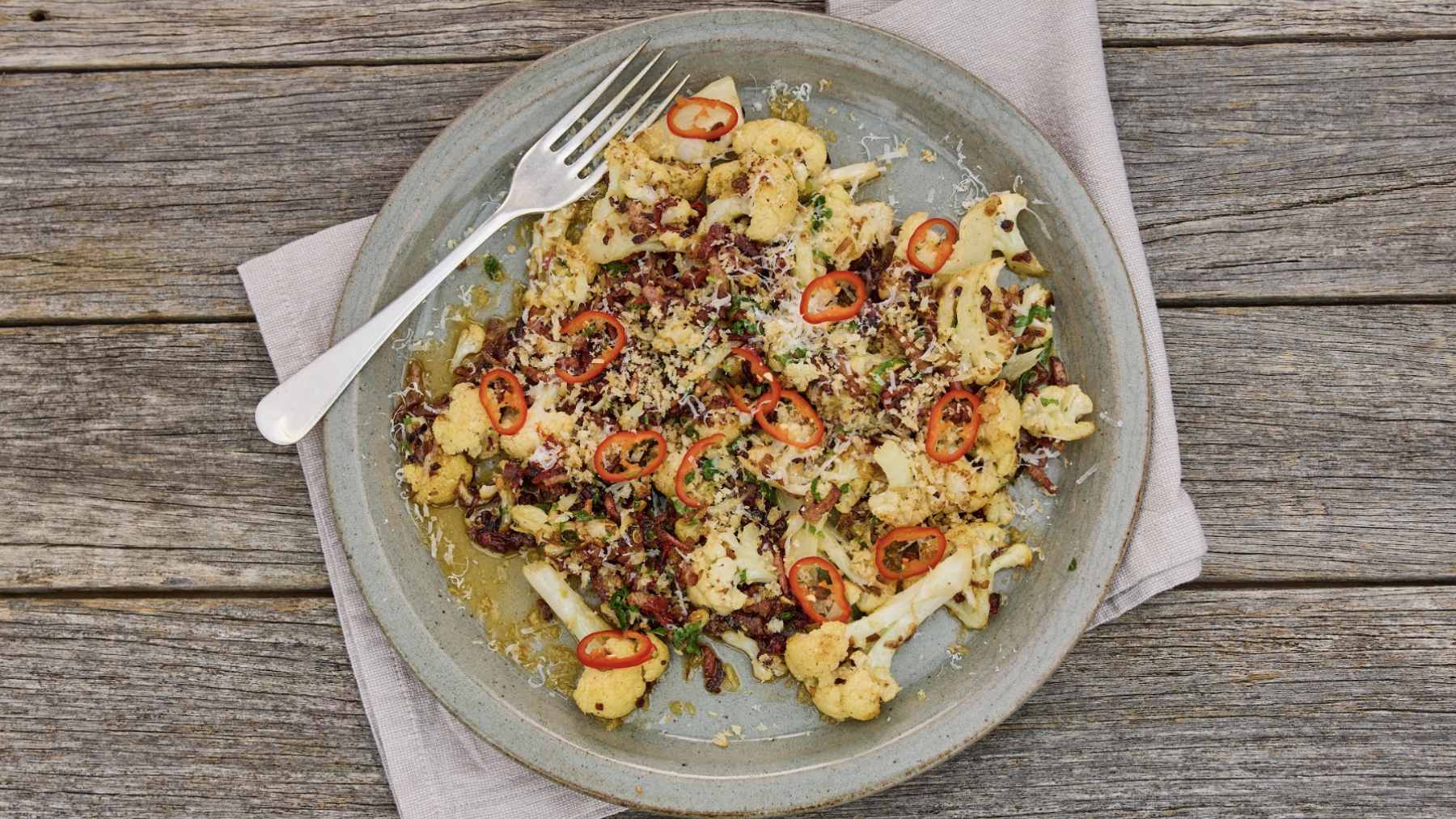 The great-grandma favorite almost nobody cooks anymore is one of those dishes that refuses to disappear 1 A whole tender cauliflower topped with creamy white sauce, crispy bacon bits, and fresh parsley, served as a classic Danish comfort dish.
