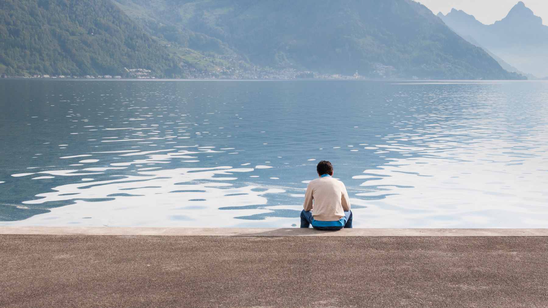 A person sitting at a desk appearing thoughtful and slightly disconnected, reflecting the experience of feeling lonely despite being surrounded by obligations.