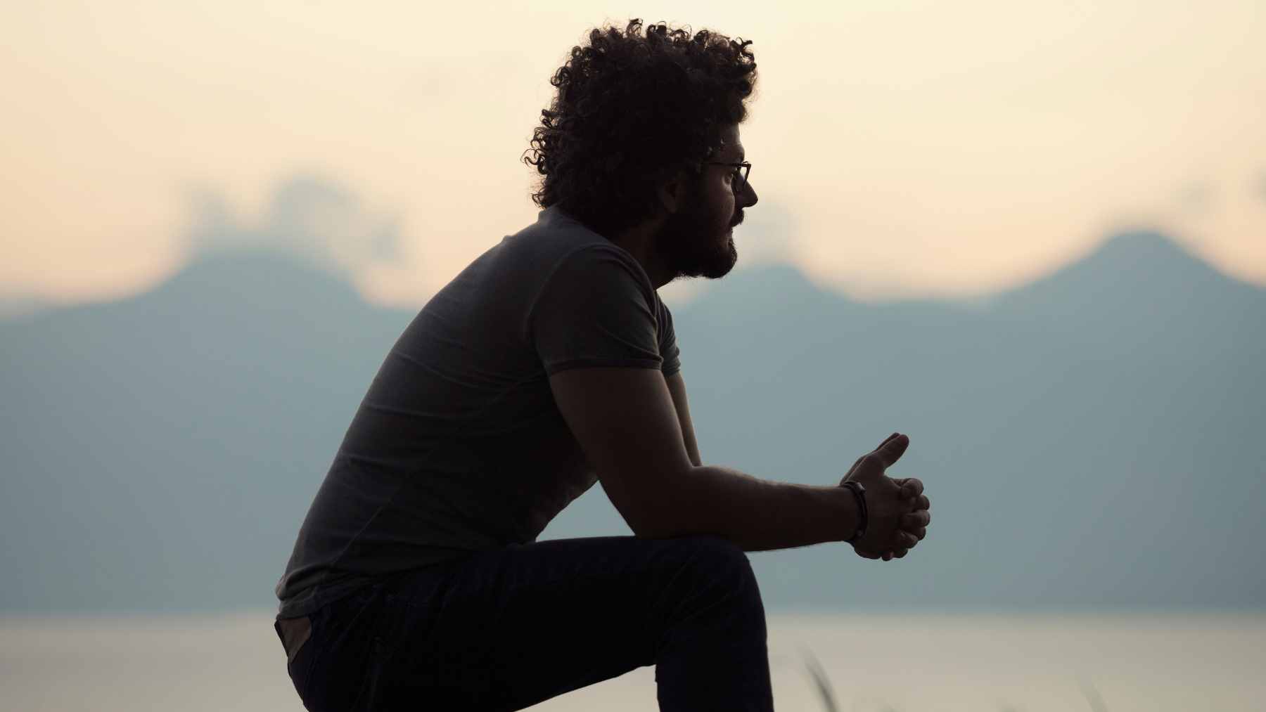 A person sitting at a desk appearing thoughtful and slightly disconnected, reflecting the experience of feeling lonely despite being surrounded by obligations.