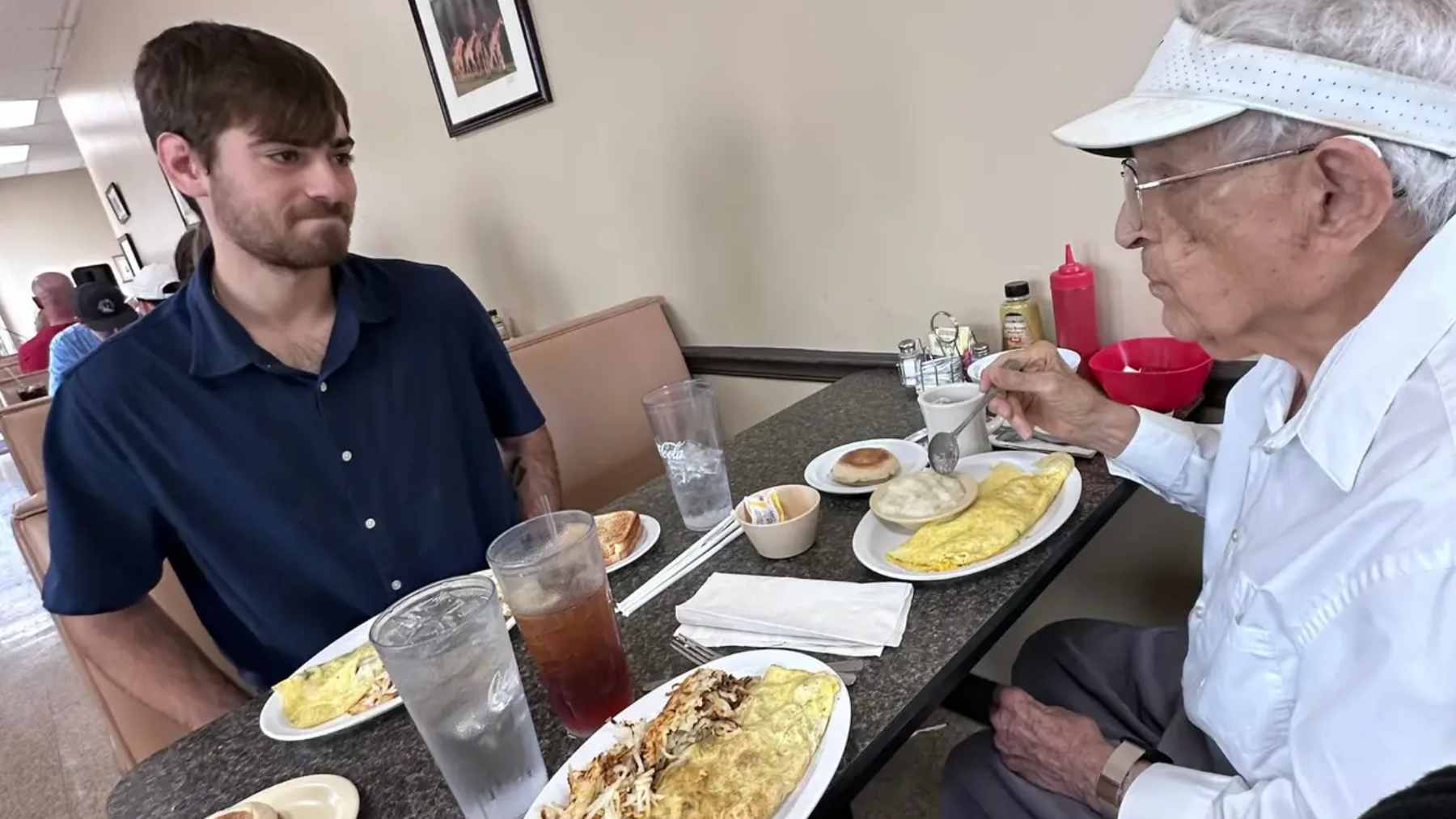 A nursing student and an elderly man engaged in a friendly game of Uno, highlighting the intergenerational connection formed through caregiving.