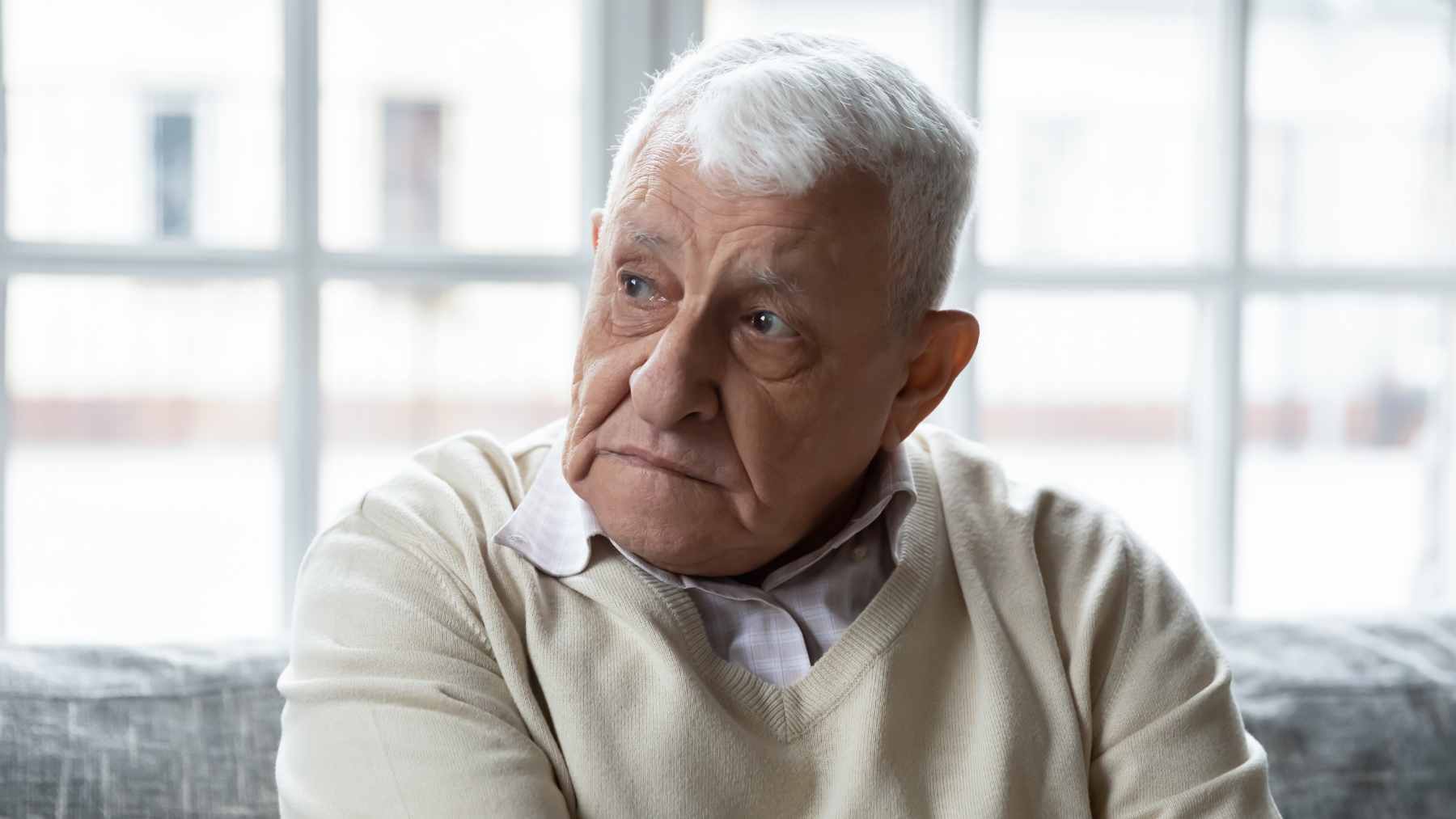An older adult looking thoughtful while considering a variety of health supplements, including omega-3 fish oil capsules.