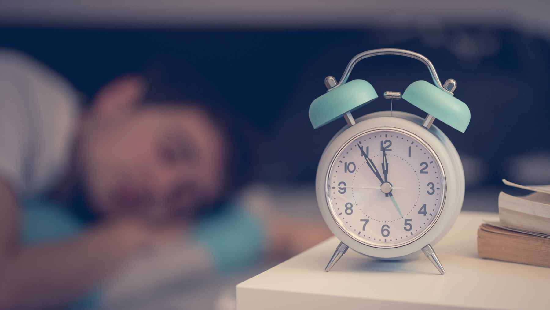 A person taking a brief, timed afternoon power nap in a quiet, dimly lit room to boost cognitive performance and alertness.