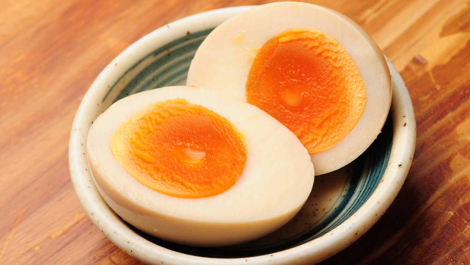 A close-up view of a perfectly cooked egg cut in half, showing a creamy, spreadable yolk and a firm white prepared using the periodic cooking method.