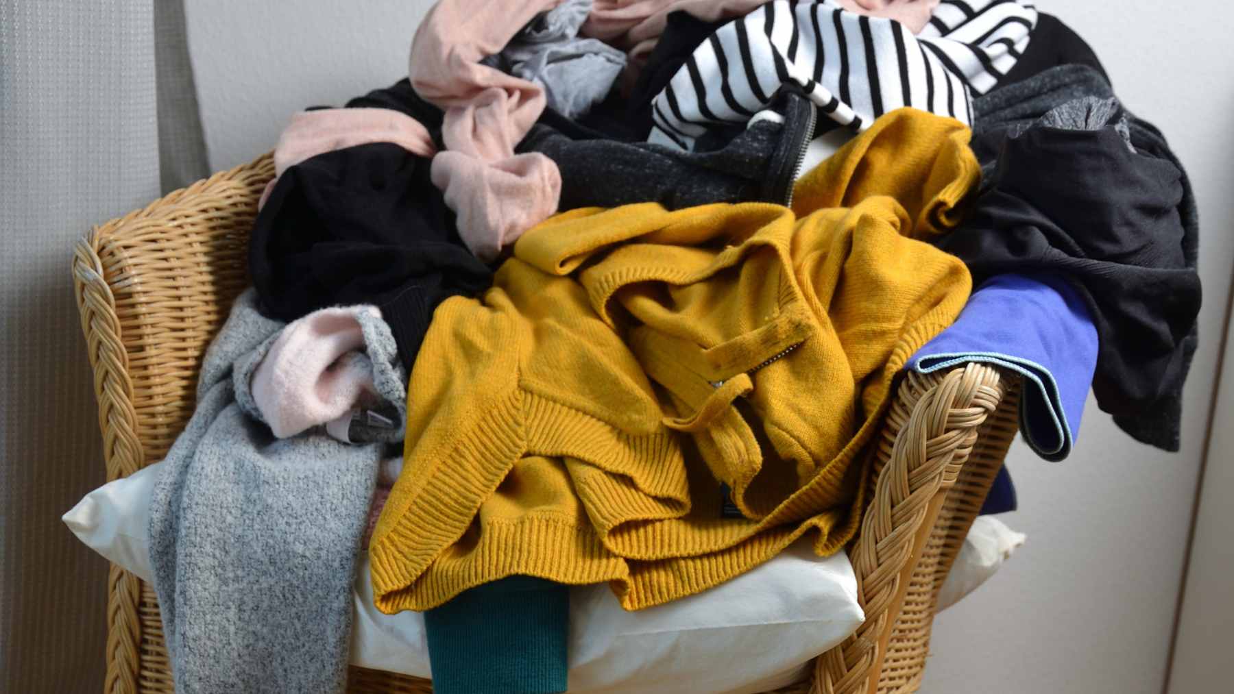 Psychology says people who pile clothes on a chair aren’t always just messy, they may be stuck in something more mental than domestic 1 A bedroom chair piled high with various articles of clothing, illustrating the common "worn once" laundry habit.