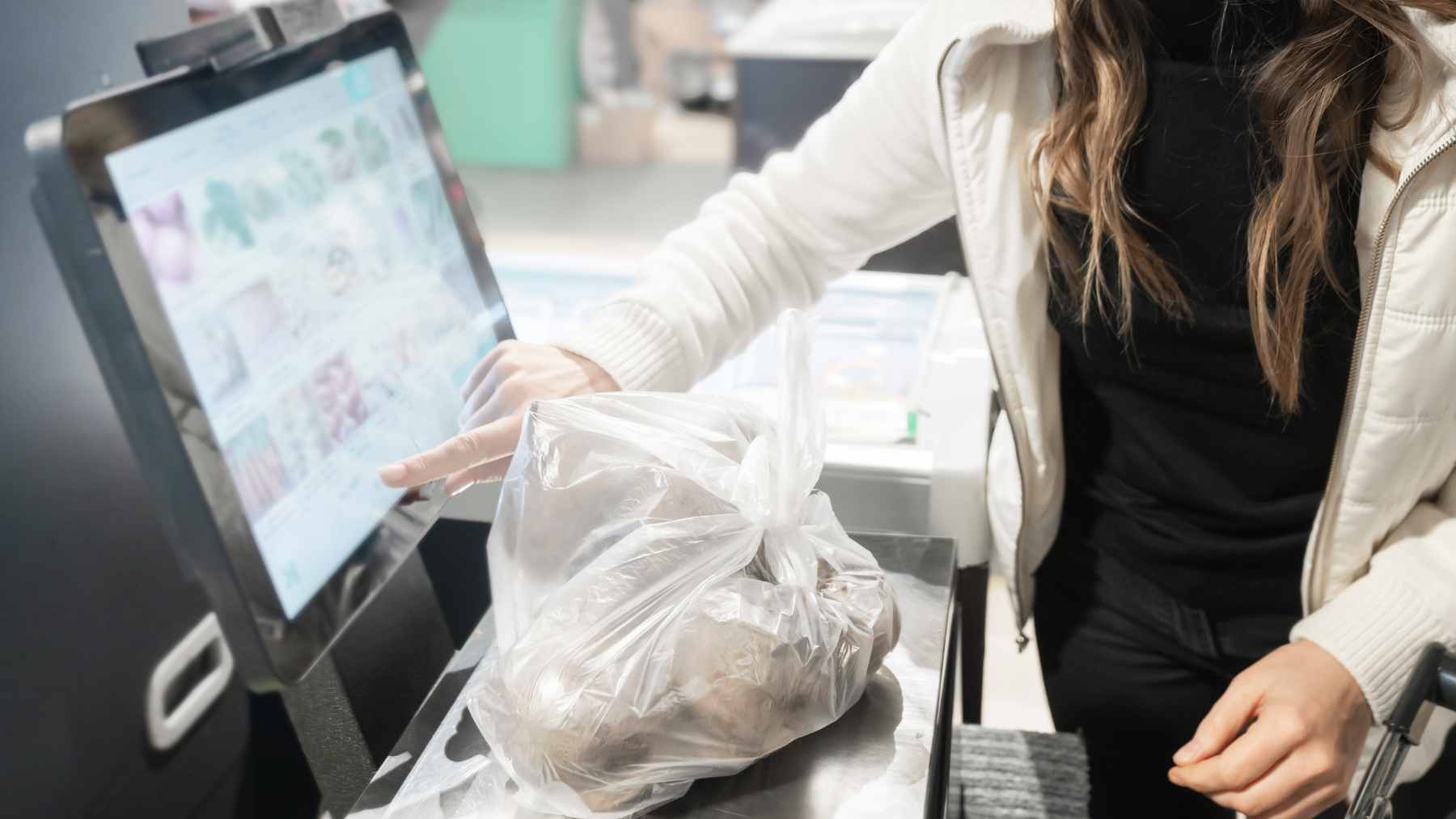 A shopper choosing to wait in a staffed checkout line with a cashier instead of using nearby empty self-checkout kiosks.