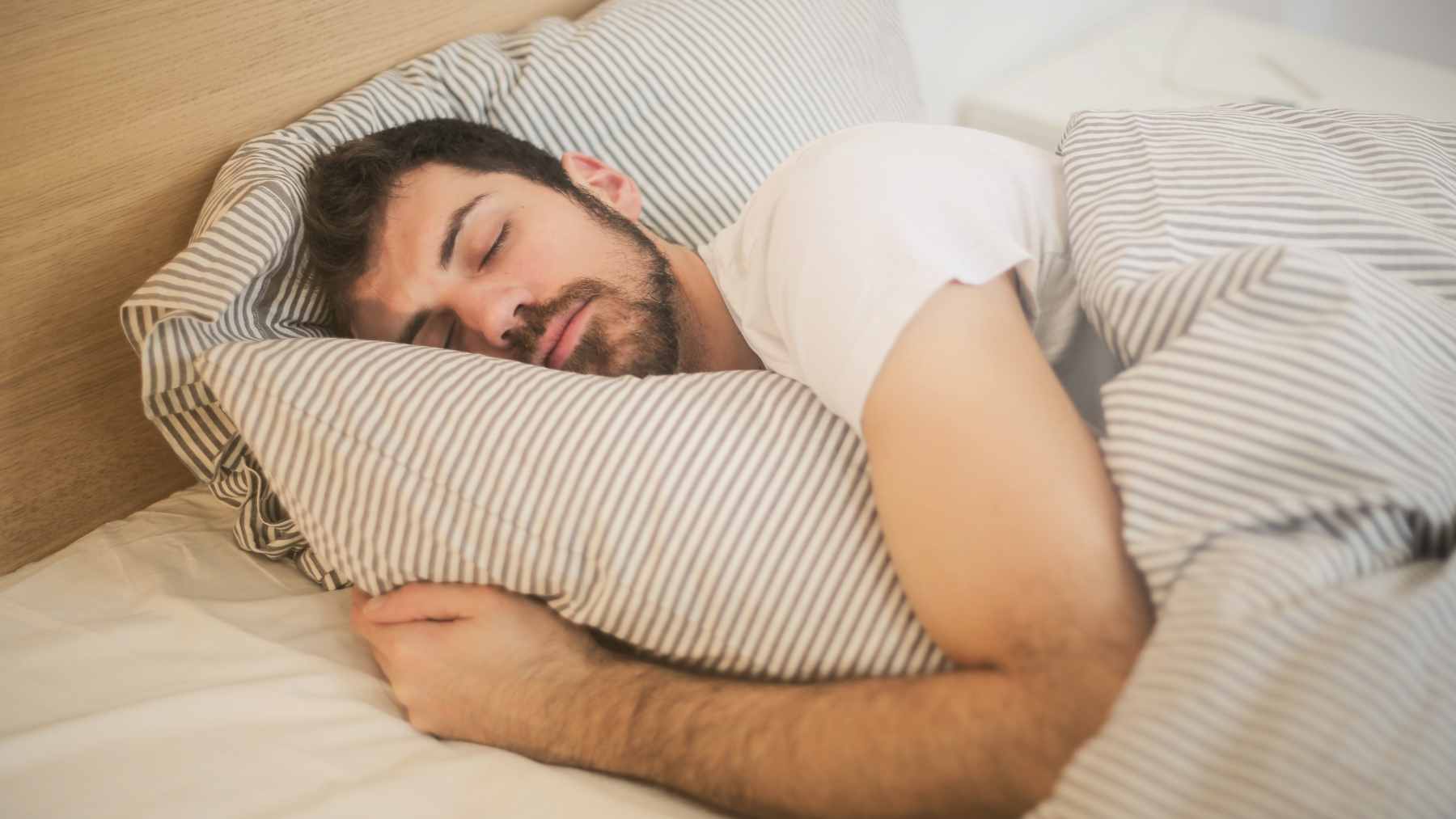 A person looking refreshed while waking up to morning sunlight, illustrating the benefits of a consistent sleep schedule.
