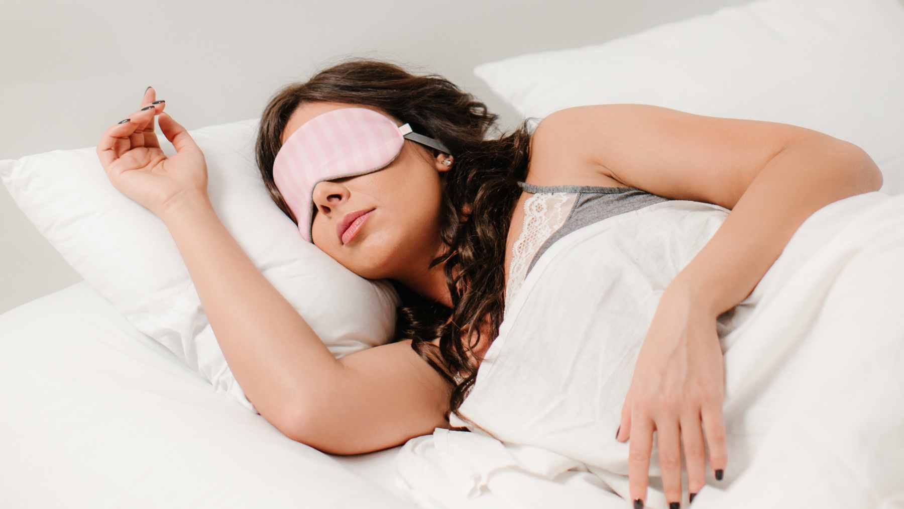A person sleeping in a warm room with a light blanket pulled up to their shoulders, illustrating the need for comfort.