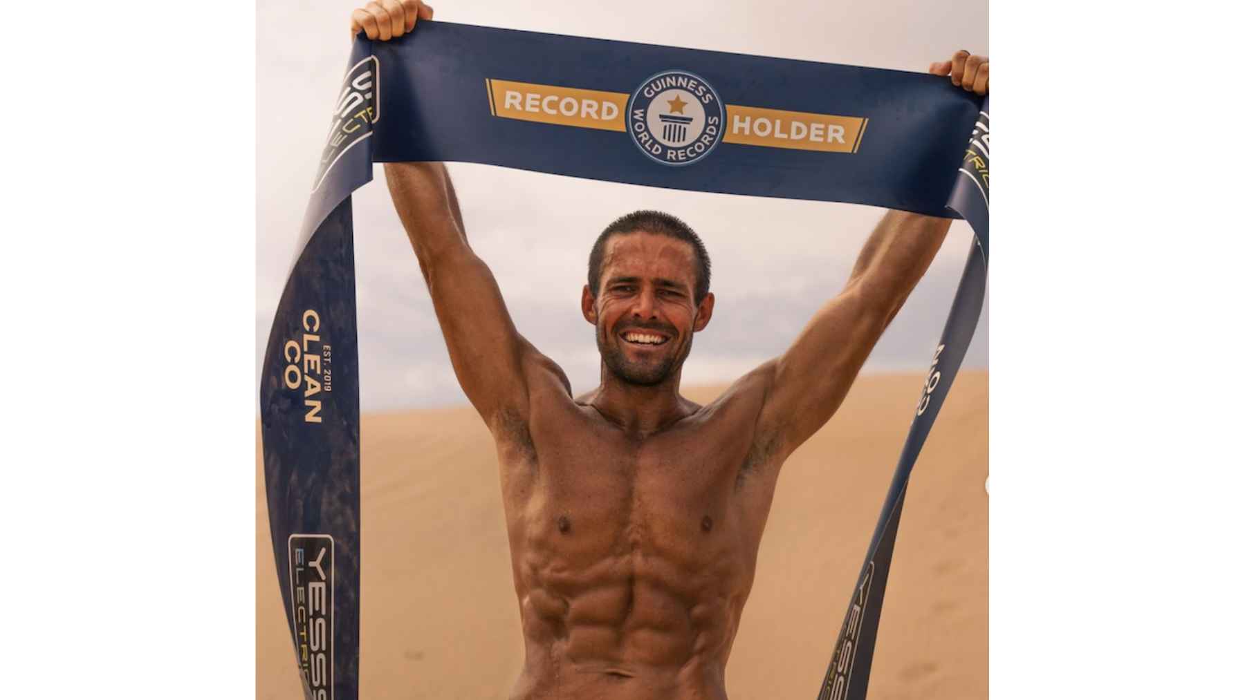 Spencer Matthews celebrates with a Guinness World Records banner after completing his record-breaking endurance marathon challenge in the Jordanian desert.