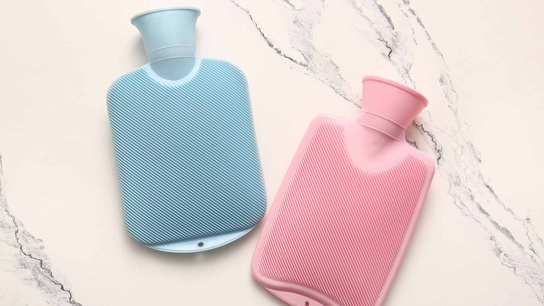 A chilled hot water bottle wrapped in a soft towel, placed at the foot of a bed to provide relief from summer heat.