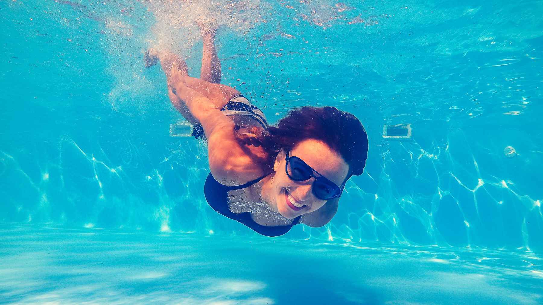 Person swimming laps in a pool as part of a low-impact workout that supports cardiovascular fitness and mental well-being.