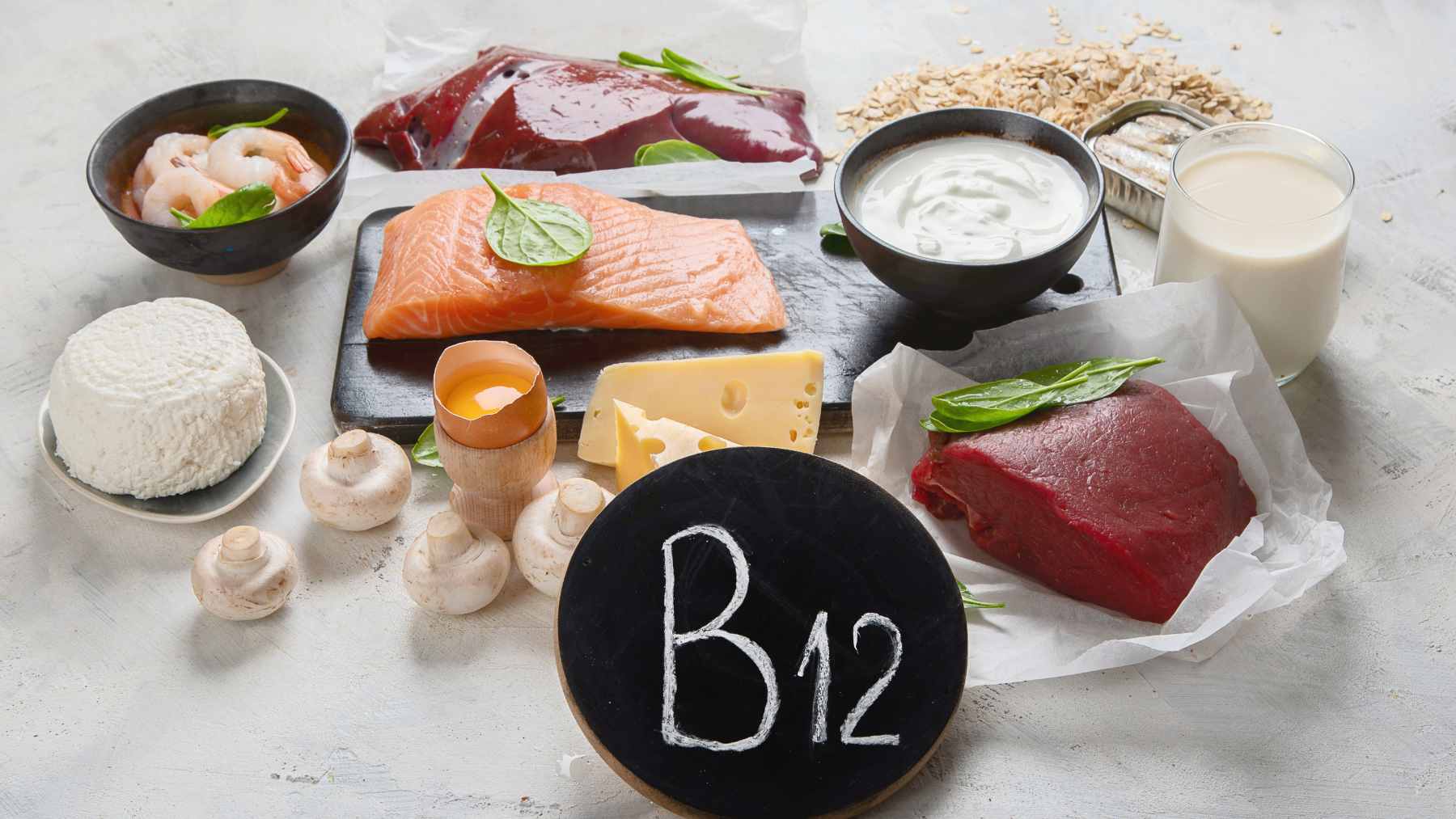 A colorful assortment of B12-rich foods, including salmon, eggs, yogurt, and spinach, presented on a wooden table to highlight dietary sources of the nutrient.
