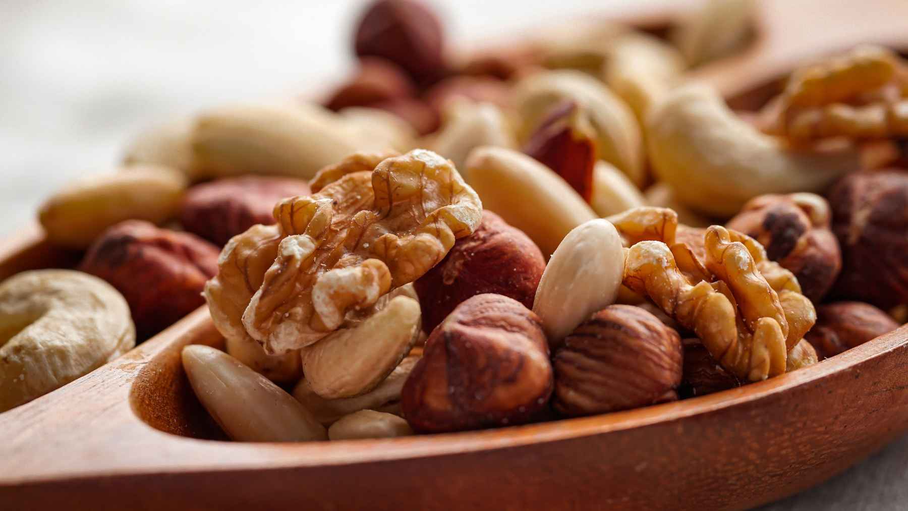Wooden bowl filled with walnuts, almonds, hazelnuts, and other mixed nuts known for their heart and brain health benefits