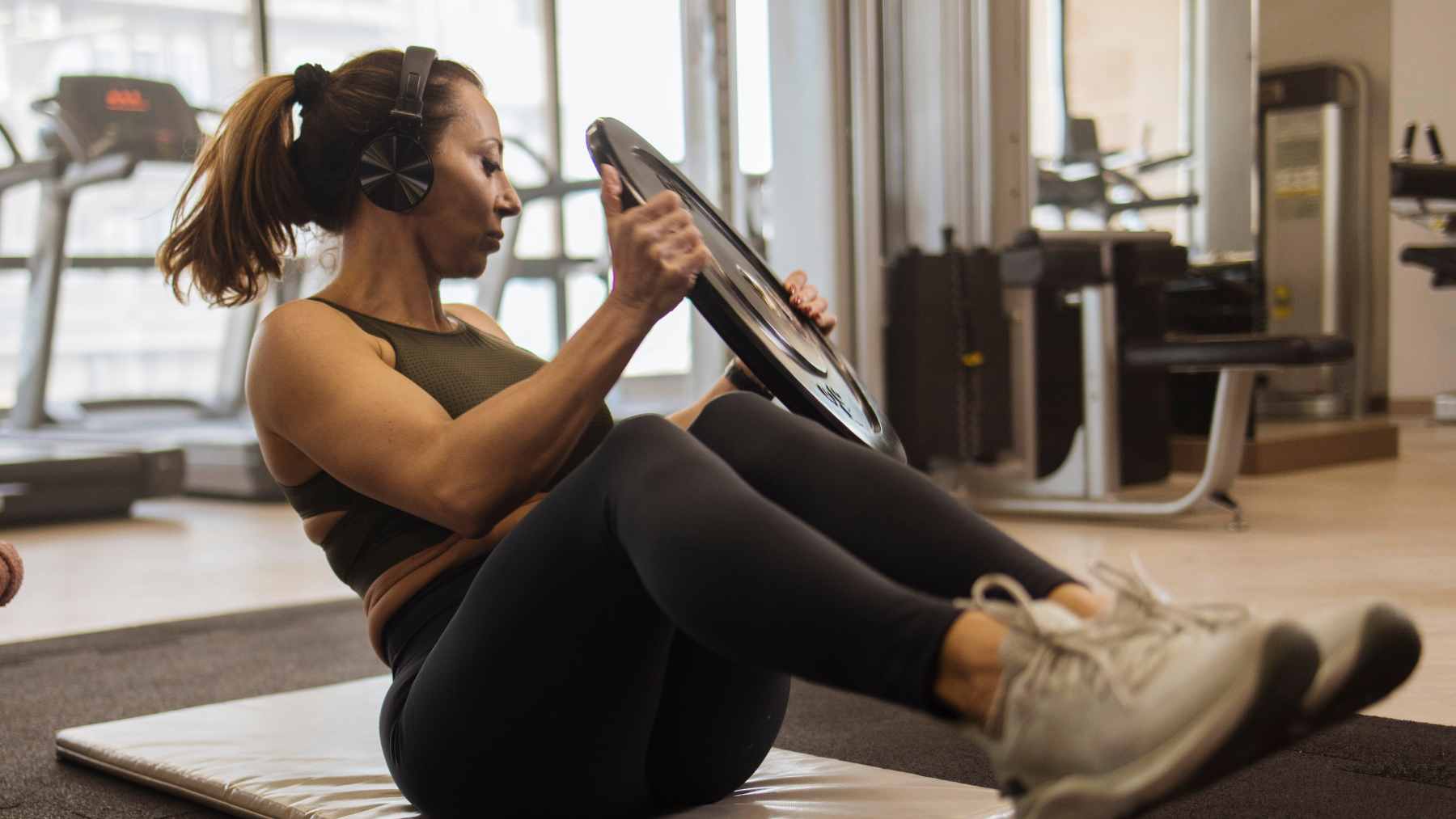 A middle-aged man cycling on a stationary bike while wearing headphones and focusing on his workout.