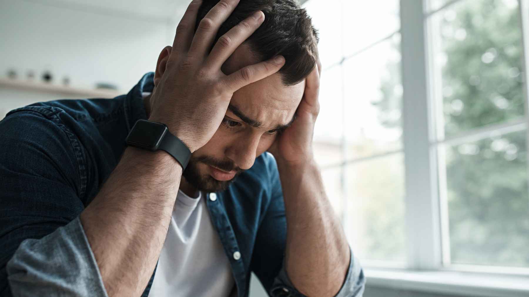 Person sitting alone indoors while looking toward the outside, illustrating how agoraphobia and anxiety can make everyday situations feel overwhelming.