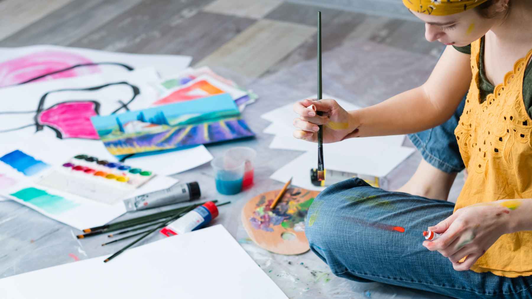 Cancer recovery is not only about medicine: drawing, clay, even music may unlock emotions patients could not say out loud 1 Person painting with brushes and watercolors during an art therapy session focused on emotional expression and well-being.