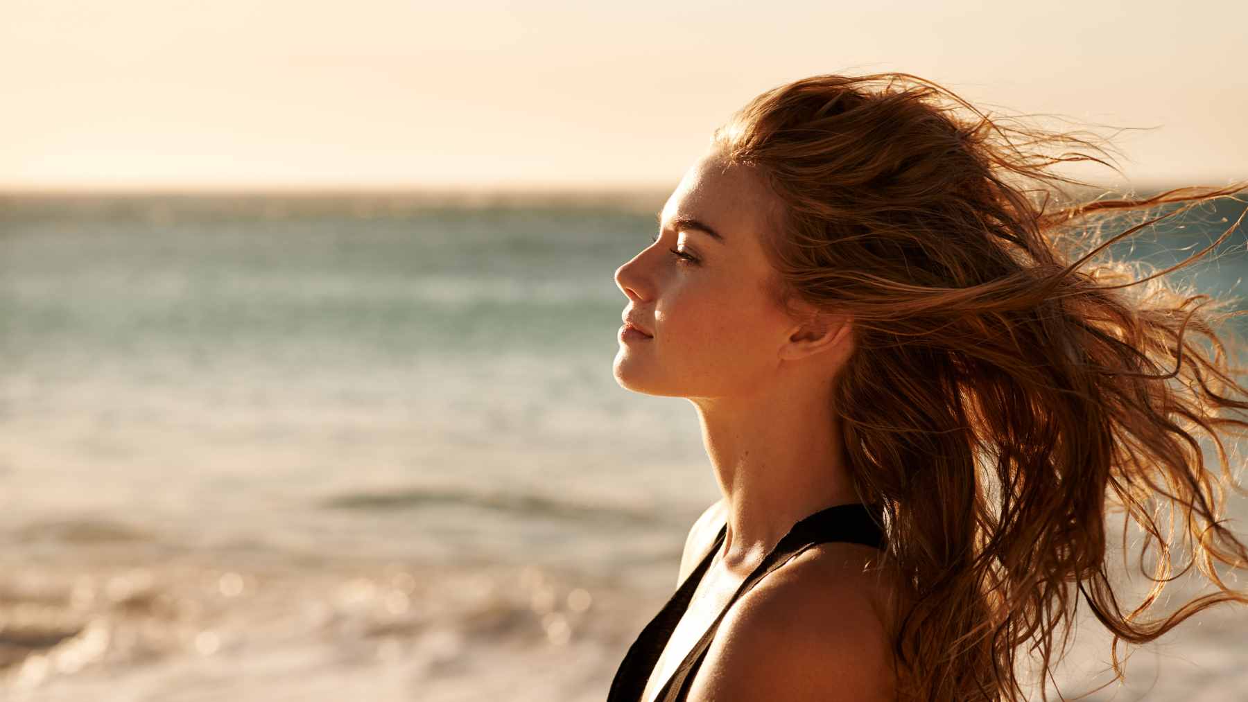 It's not the sea that strengthens your bones, it's the three things the beach quietly gives you 1 A person walking along the sandy shoreline at sunrise, representing the gentle physical activity and sunlight exposure that benefits bone health.