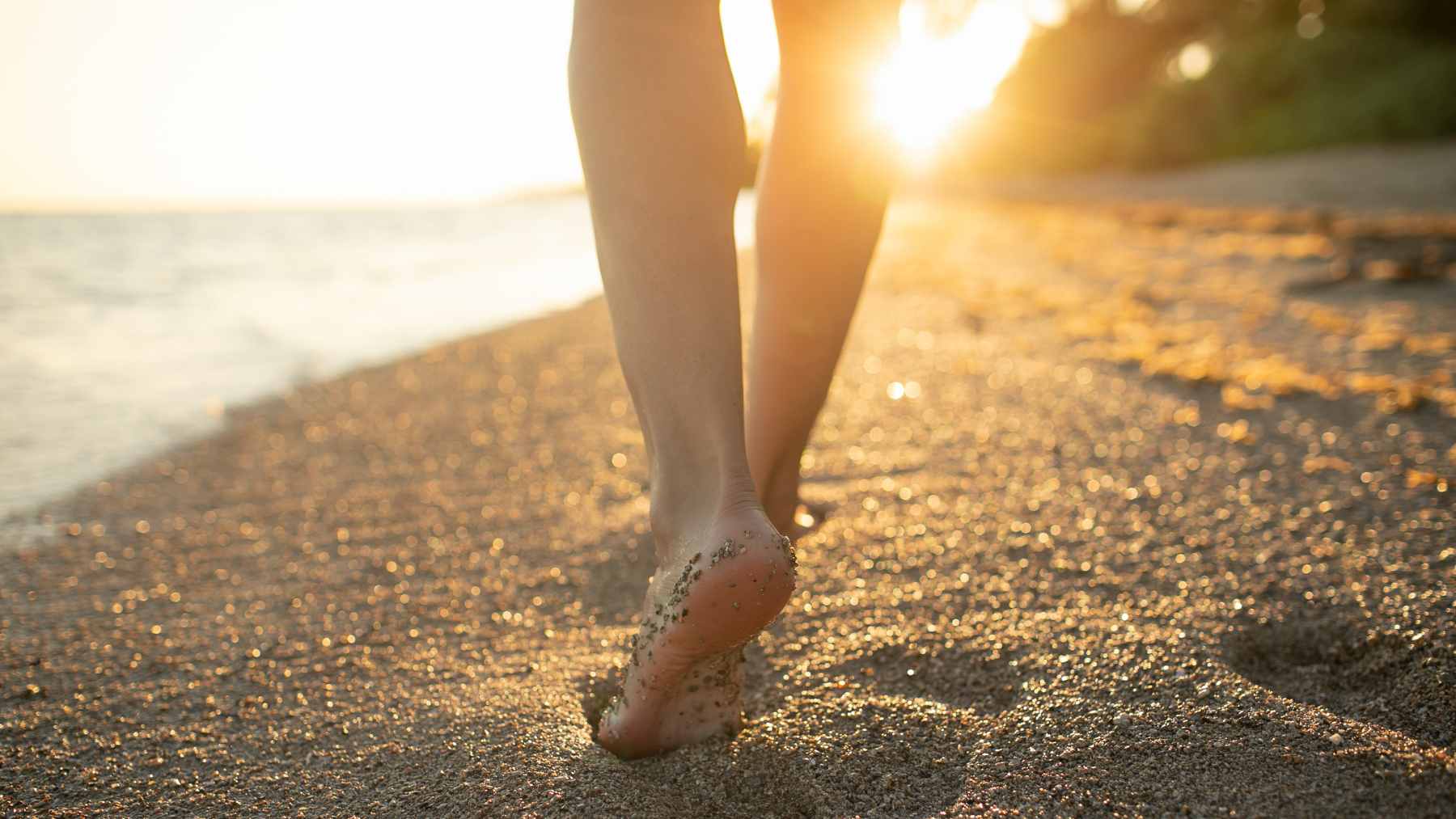 It's not the sea that strengthens your bones, it's the three things the beach quietly gives you 2 A person walking along the shoreline on a sunny day, representing the benefits of outdoor movement and moderate sunlight exposure for bone health.