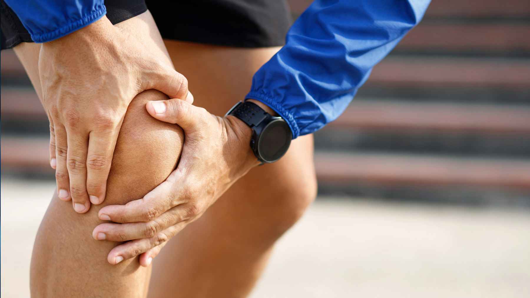 Doctor points to a knee joint model while explaining cartilage damage and osteoarthritis during a medical consultation.