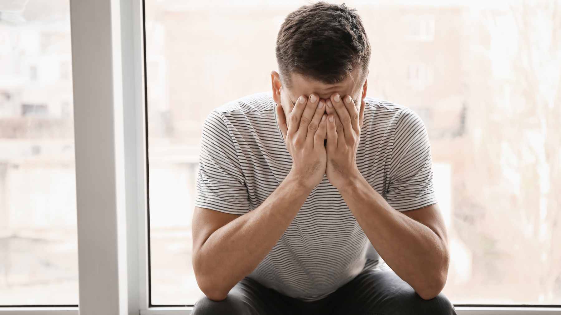 A person sitting quietly with a phone, representing the communication challenges and subtle vocal changes associated with depression.