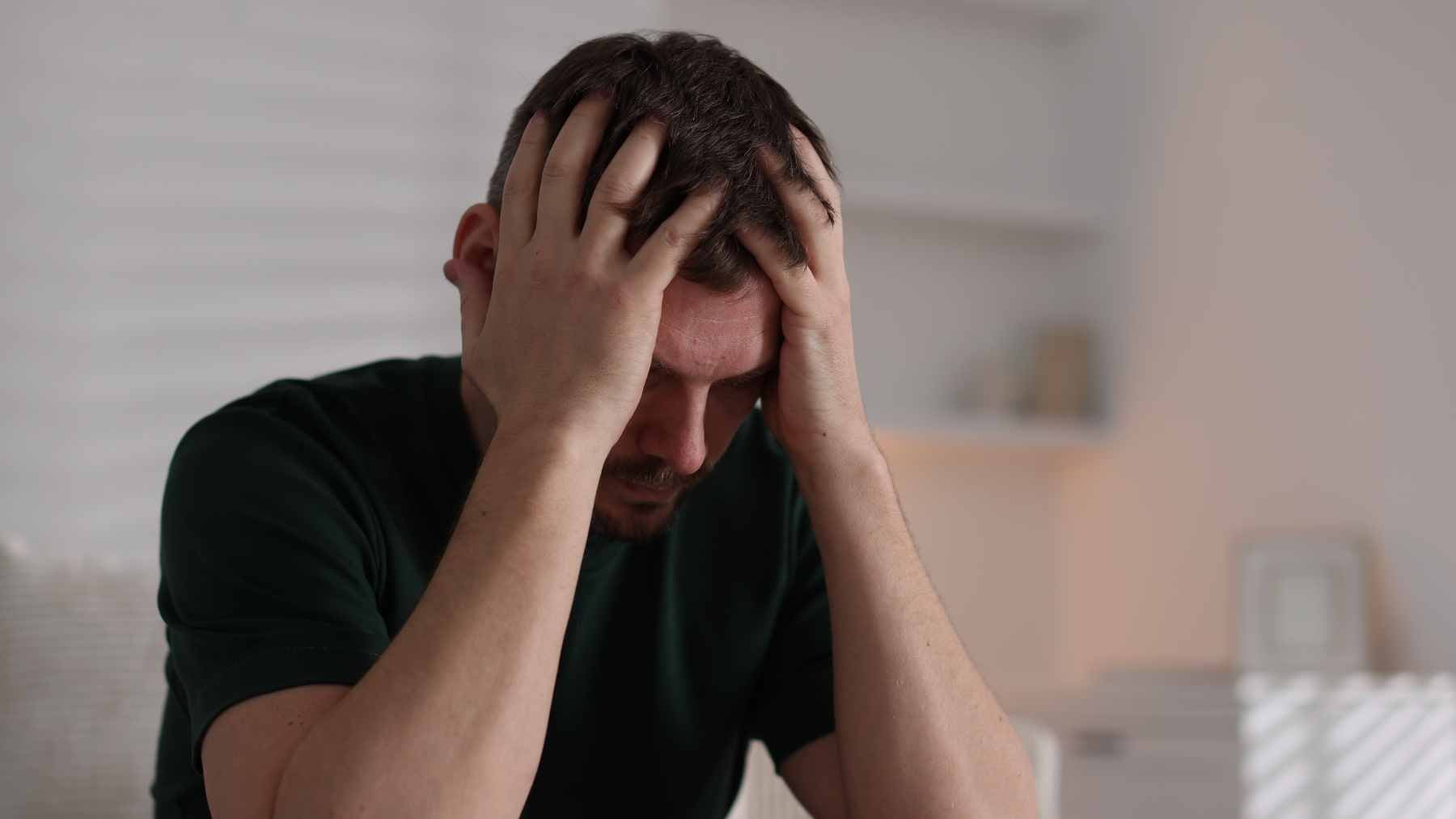 A person sitting quietly with a phone, representing the communication challenges and subtle vocal changes associated with depression.