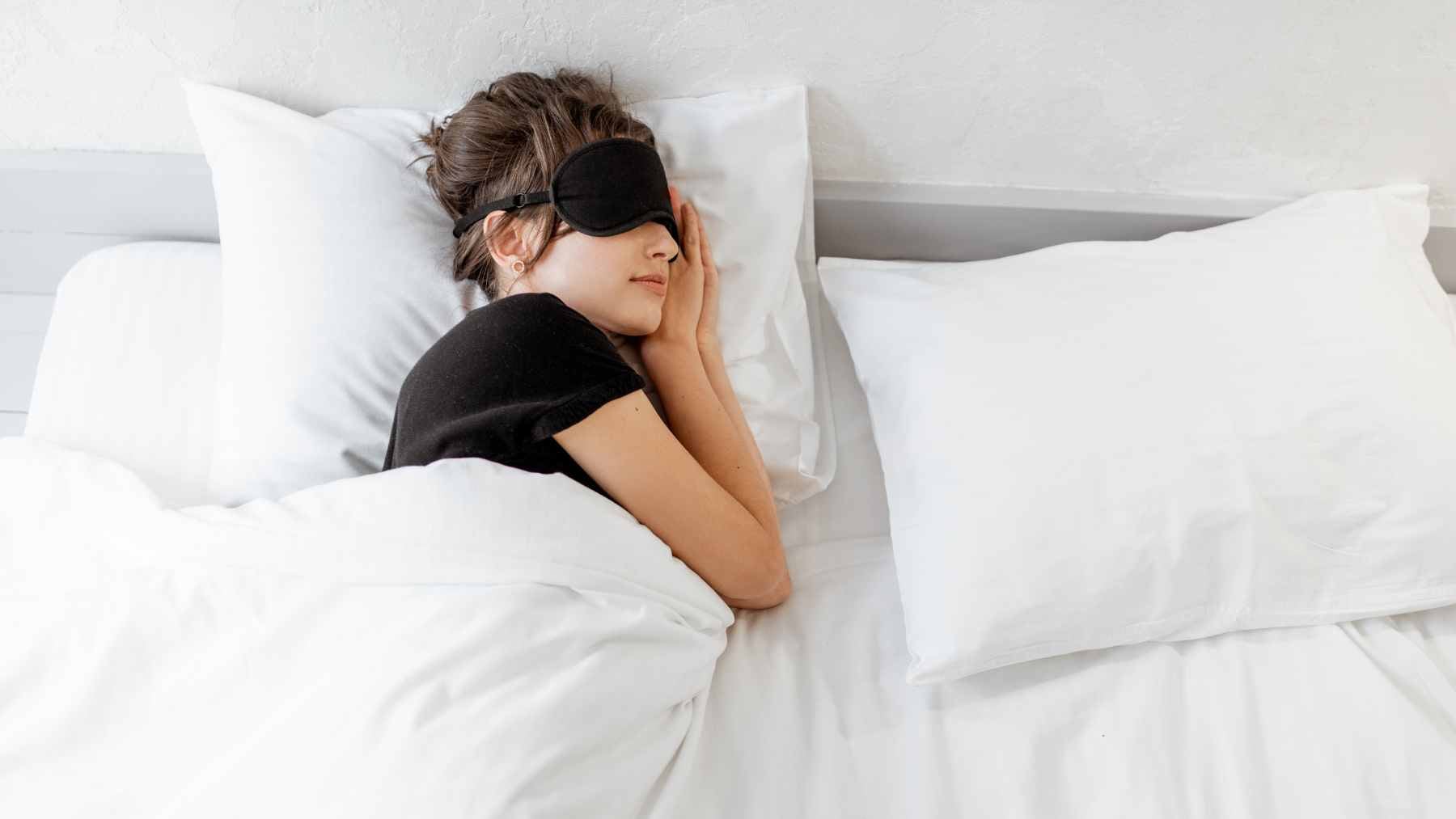 Sleeping under seven hours may shorten your life more than a poor diet or no exercise, a result researchers say they did not expect 1 A person waking up looking tired in a dimly lit bedroom, representing the impact of chronic sleep deprivation on health.