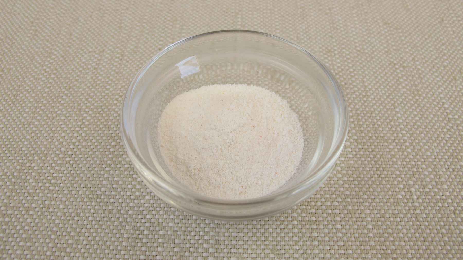 A glass of water with white inulin powder being stirred with a spoon, highlighting health and prebiotic supplements.