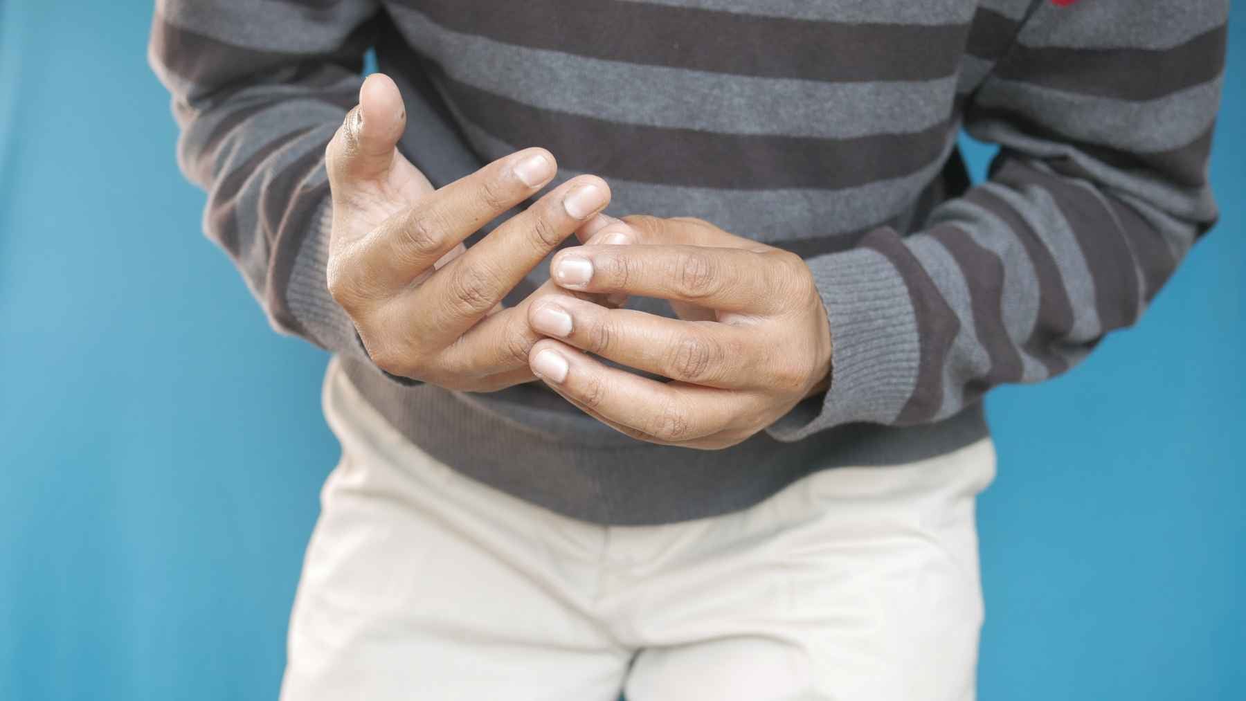 A person holding their aching knee, representing joint pain evaluation to differentiate between osteoarthritis and inflammatory arthritis.