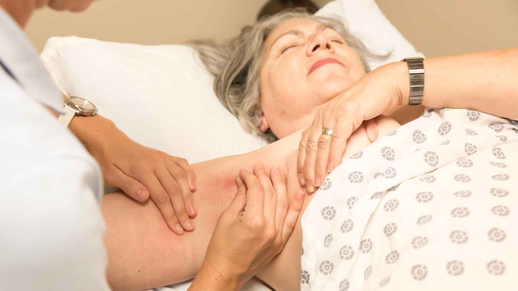 Healthcare professional fitting a compression sleeve on a patient with lymphedema, the standard treatment used to help control swelling.