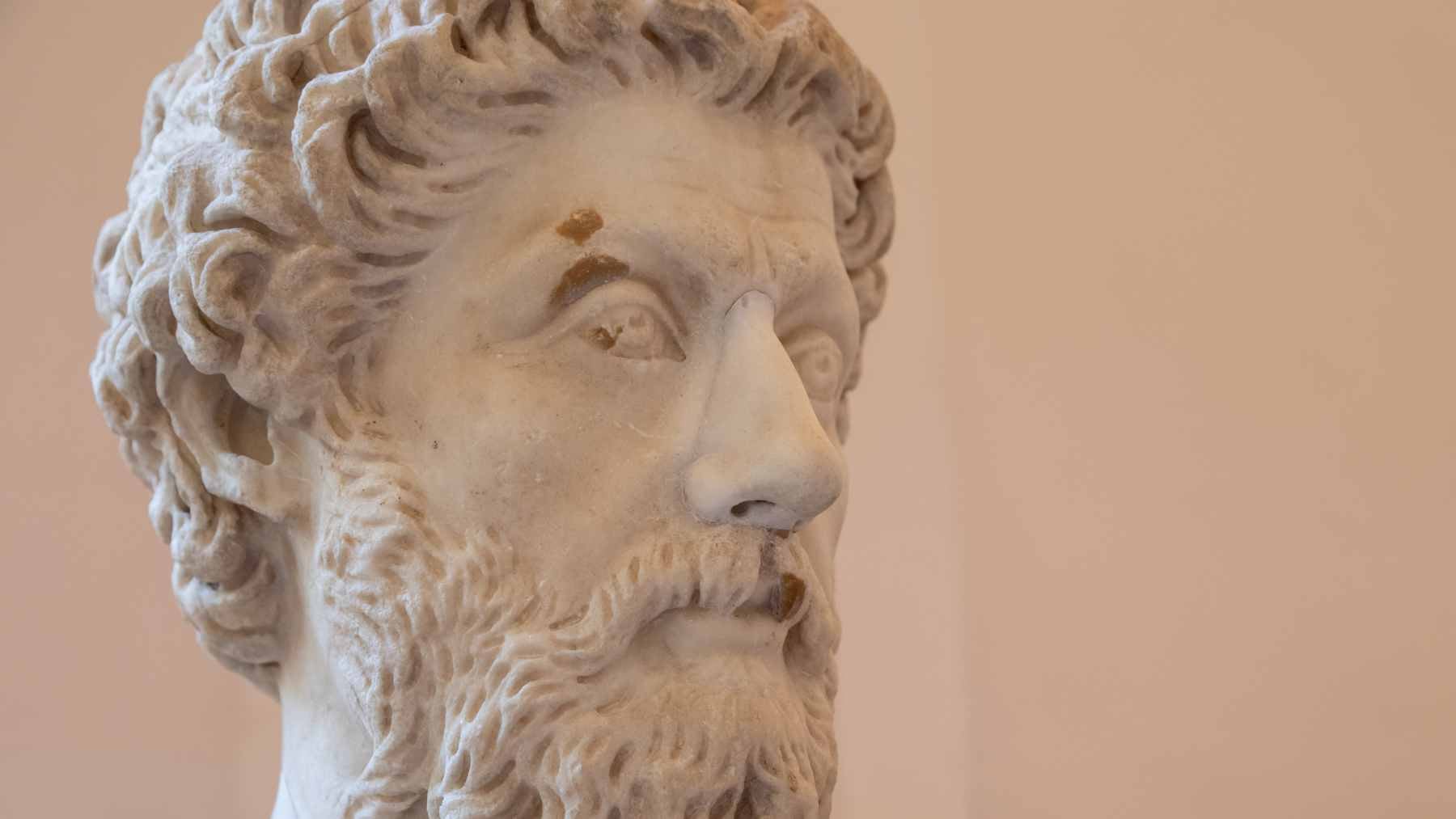 A classic marble bust of Roman Emperor Marcus Aurelius set against a neutral, contemplative background.