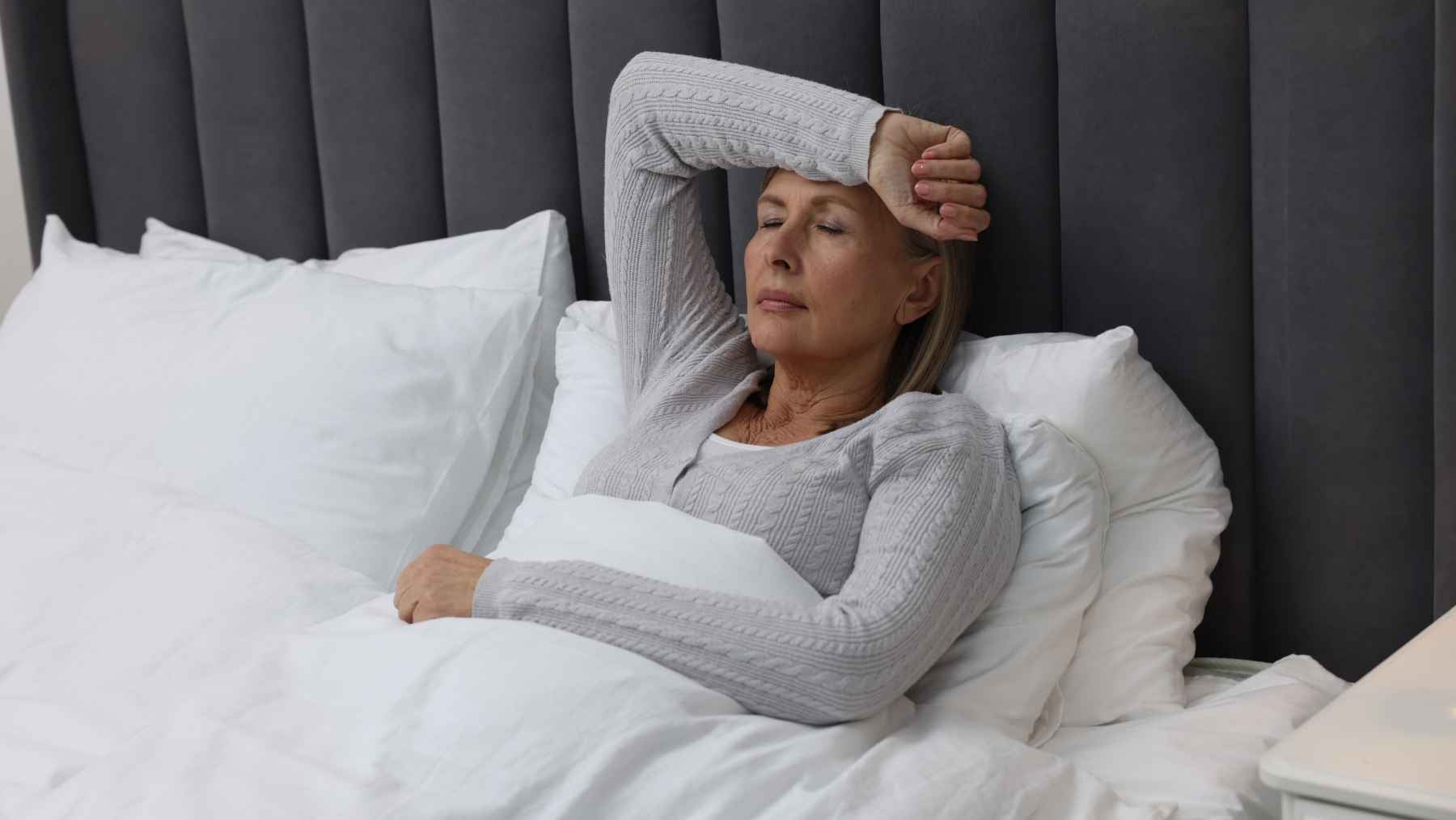Woman relaxing in a calm bedroom at night, illustrating healthy sleep habits that may help improve rest during the menopause transition.