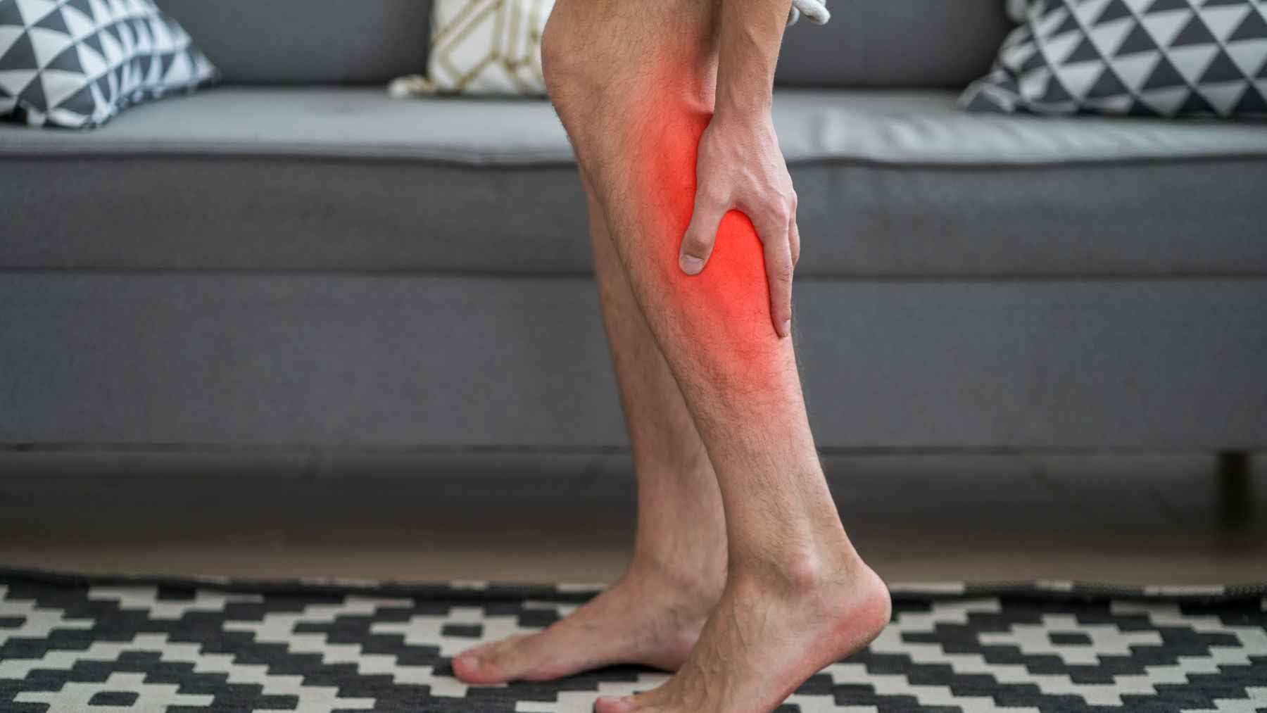 The midnight calf cramp that yanks you awake could be your muscles signaling a fix you already have at home 1 Person holding a painful calf muscle during a nighttime leg cramp, highlighting the sudden muscle spasm that commonly interrupts sleep.