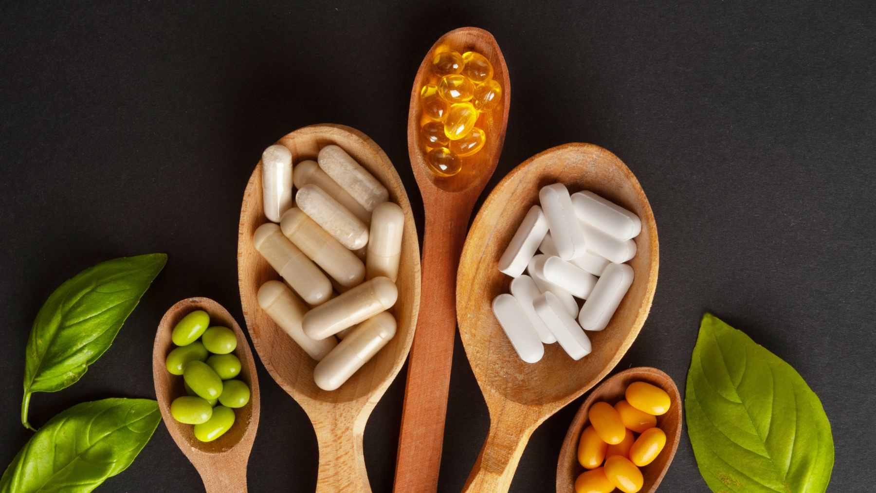 A variety of common nutritional supplements, including magnesium, omega-3 fish oil, and collagen powder, displayed on a clean wooden surface.