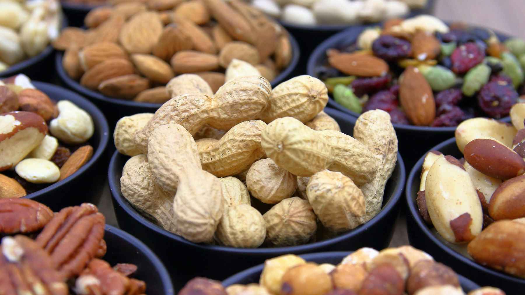 Bowls of nuts and seeds rich in omega-3 fatty acids, foods commonly recommended to support skin health and reduce inflammation.
