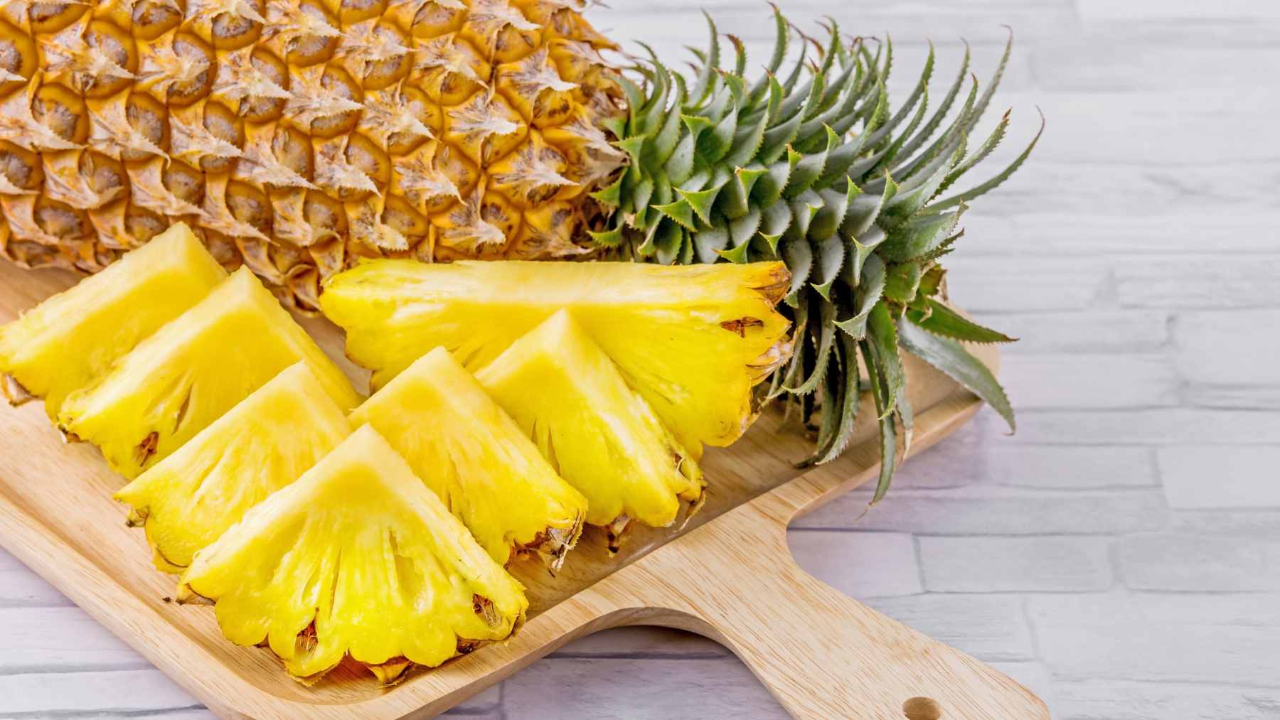 Fresh pineapple slices and chunks on a cutting board, highlighting its digestive benefits and bromelain content.
