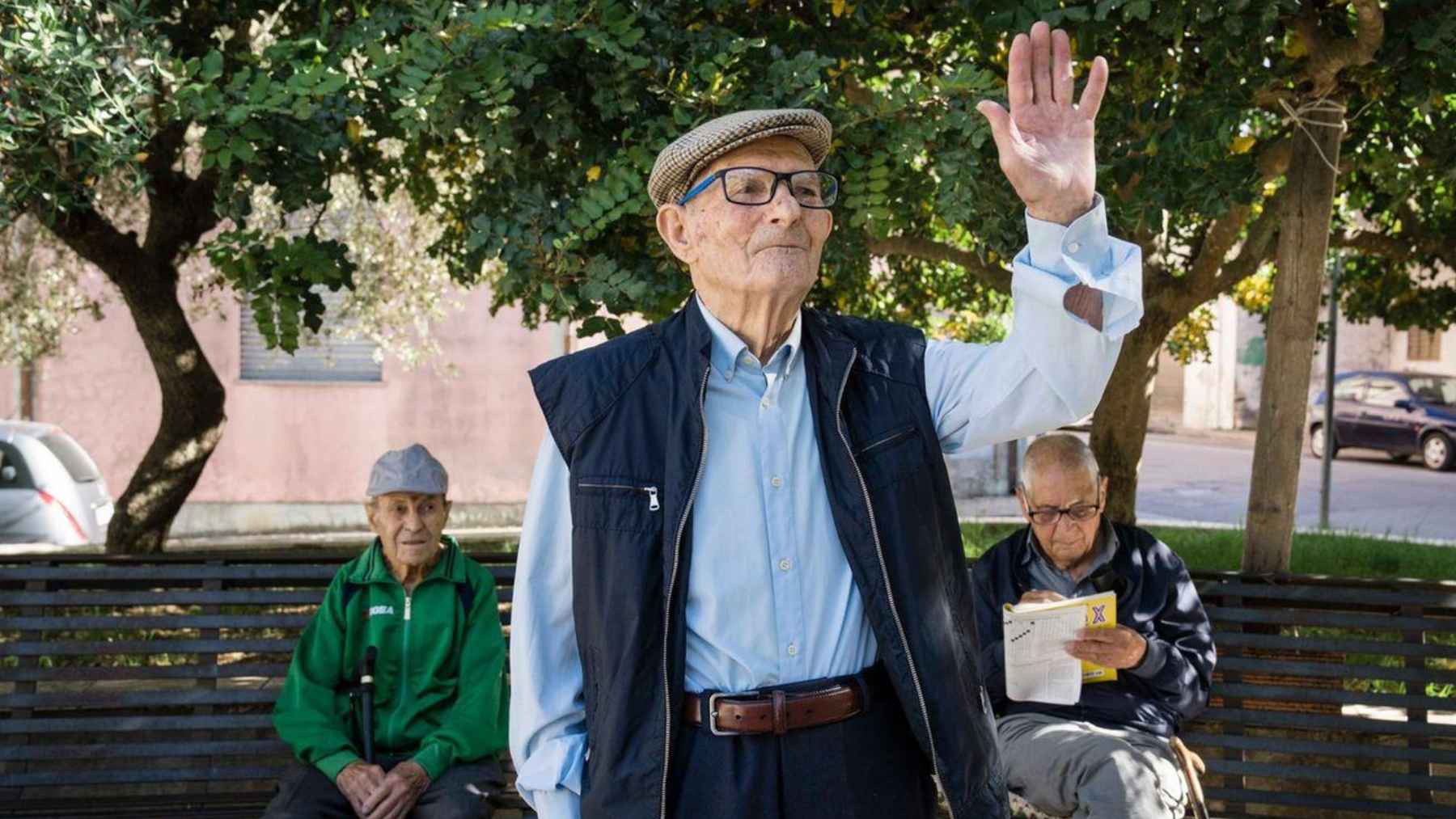 An older man in Sardinia’s Blue Zone greets people in a town square, reflecting the community’s exceptional longevity.
