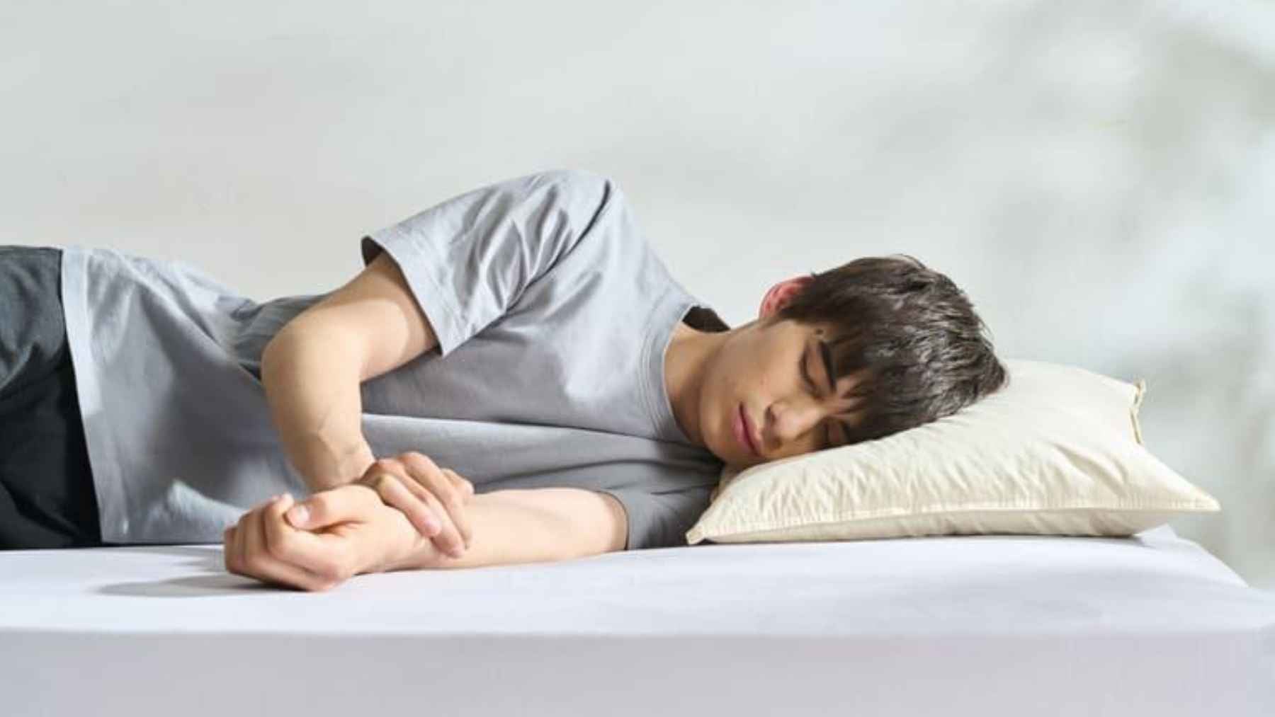 Person lying in bed demonstrating a healthy sleeping position that supports spinal alignment and improves breathing during sleep.