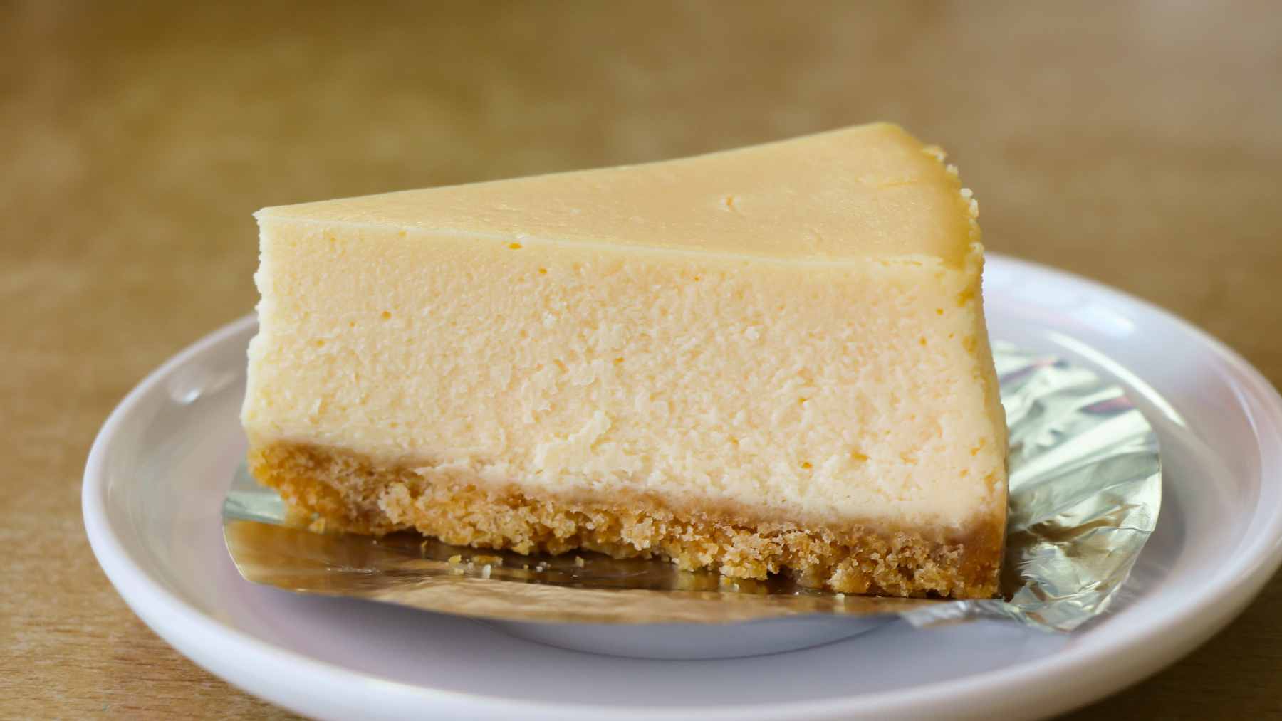 A slice of two-layered keto cheesecake featuring a rich poppy seed and nut base topped with a smooth, creamy cheese filling.