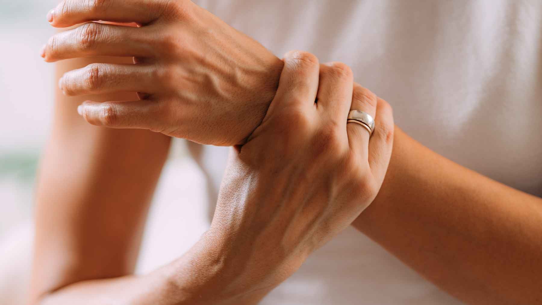 Person holding a painful wrist or knee, illustrating tendinitis caused by repetitive movements and everyday strain.