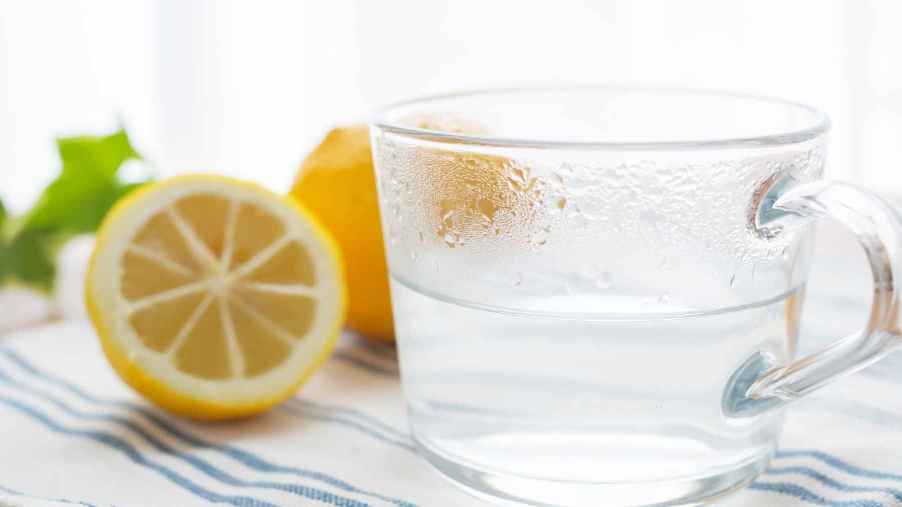 That glass of warm lemon water you sip at dawn may do more for your digestion and hydration than you ever realized 1 A mug of warm water with a slice of fresh lemon on a table, symbolizing morning hydration and wellness.