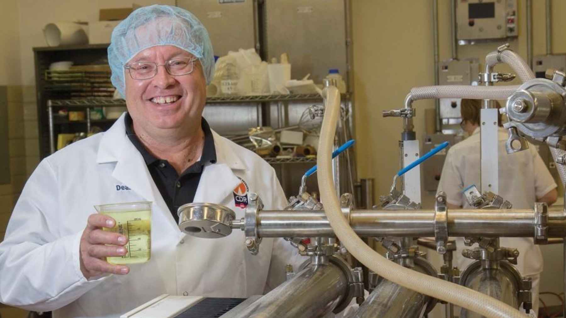 Researcher holds a sample of liquid whey inside a dairy processing facility where whey proteins are recovered for food and nutrition products.