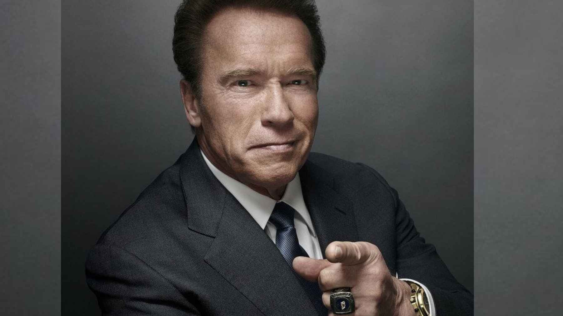 Arnold Schwarzenegger points toward the camera during a portrait promoting his message about hard work, discipline, and success.