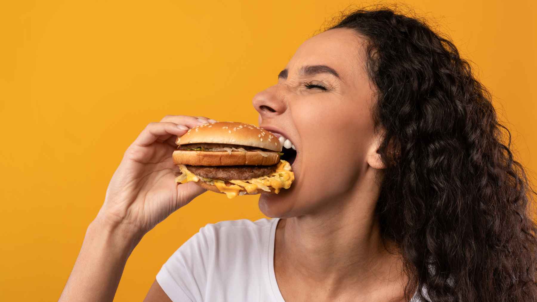 Woman eating a cheeseburger as an example of an occasional meal in a balanced diet