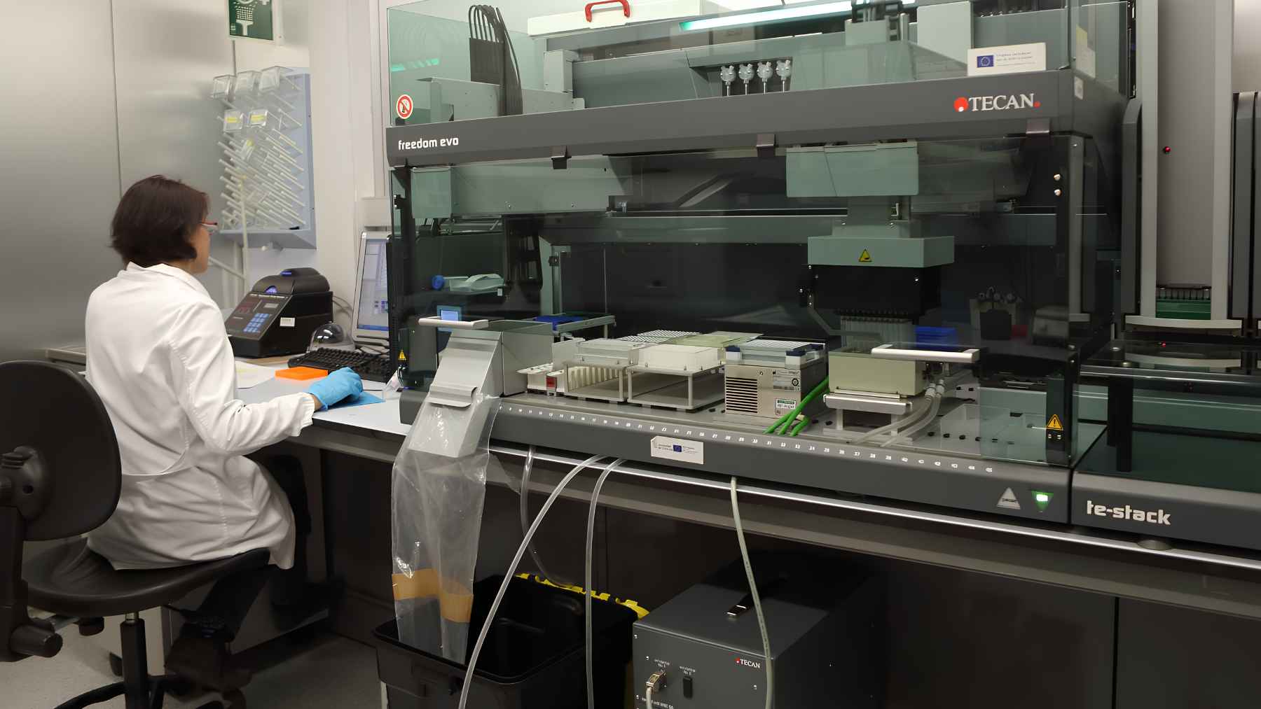 Research laboratory at the Centre for Genomic Regulation in Barcelona using automated equipment to study cancer cells and genomic data.