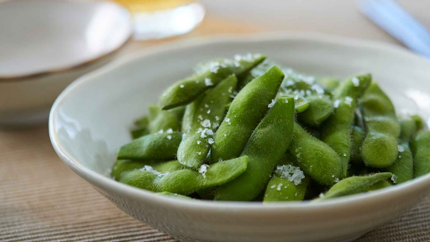 A small bowl of cooked edamame in pods, representing a heart-healthy snack with plant protein and fiber recommended by cardiologists and dietitians.