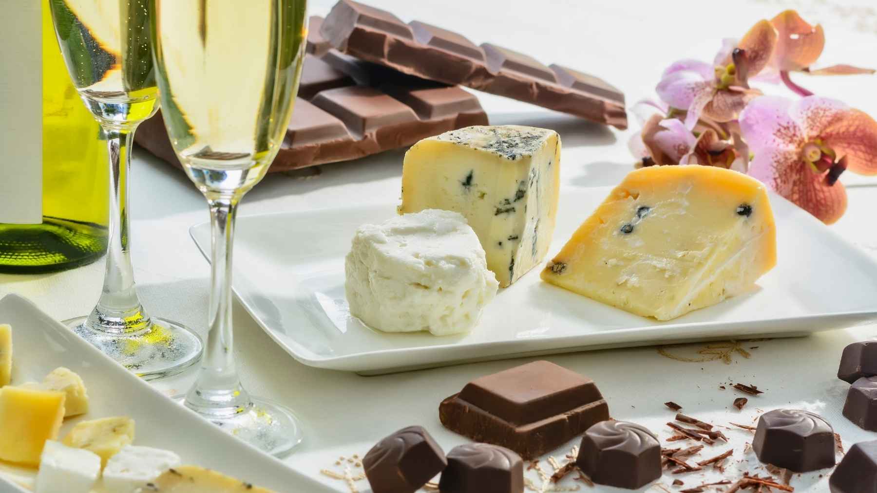 Juan Manuel Ceballos, neurologist: be careful with aged cheese, chocolate and wine, because all three set off a migraine 1 Red wine, dark chocolate, and aged cheese arranged on a table, representing common dietary migraine triggers.