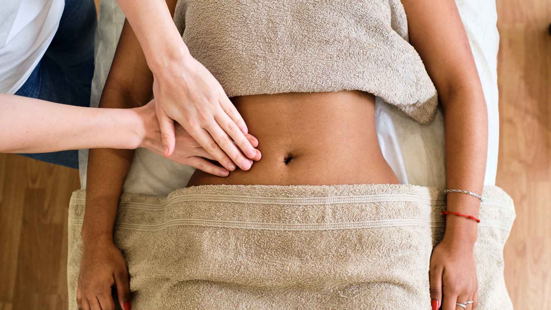 Woman receiving a gentle abdominal lymphatic massage as part of a wellness